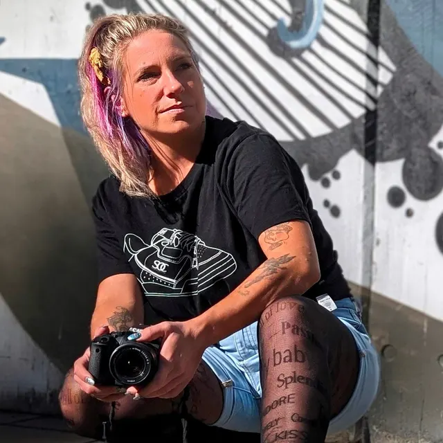 Larissa mit ihrer Kamera vor einer Graffiti-Wand